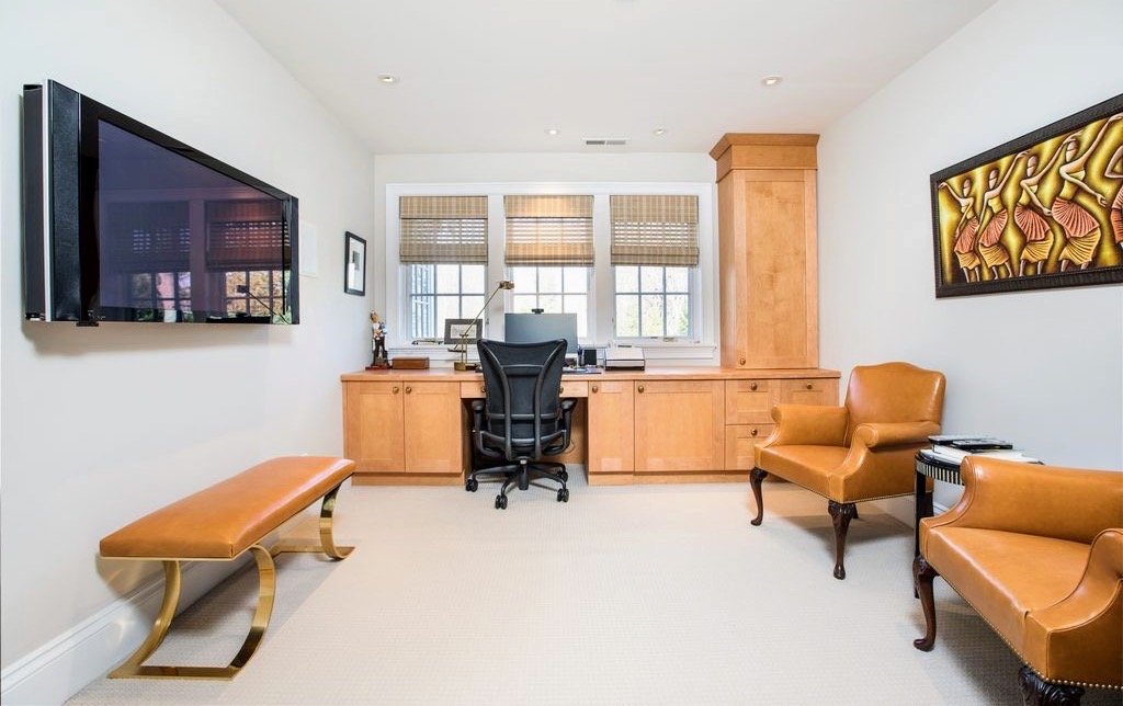 Home office with a built-in maple desk, a leather bench, and carved wood wall art