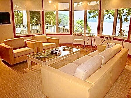 Lakeview family room with cream sofas and a glass table framed by windows over the water