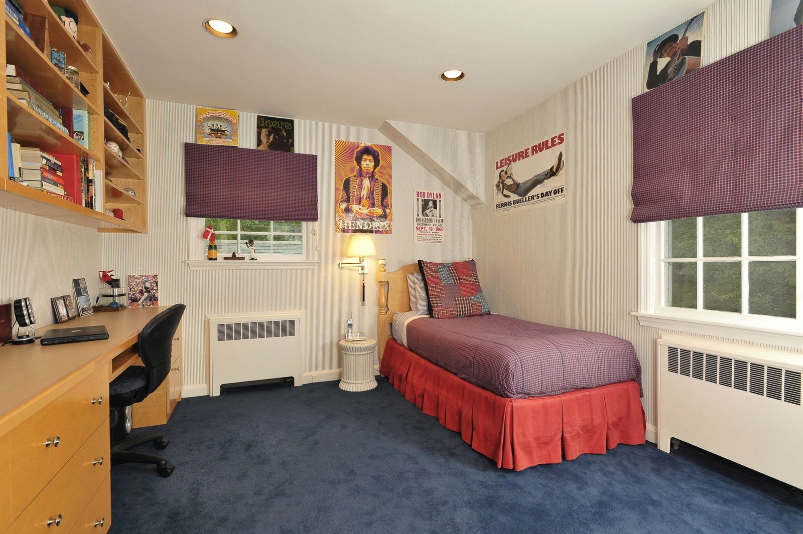 Teenager's room with music posters, a plaid coverlet, and a built-in maple desk