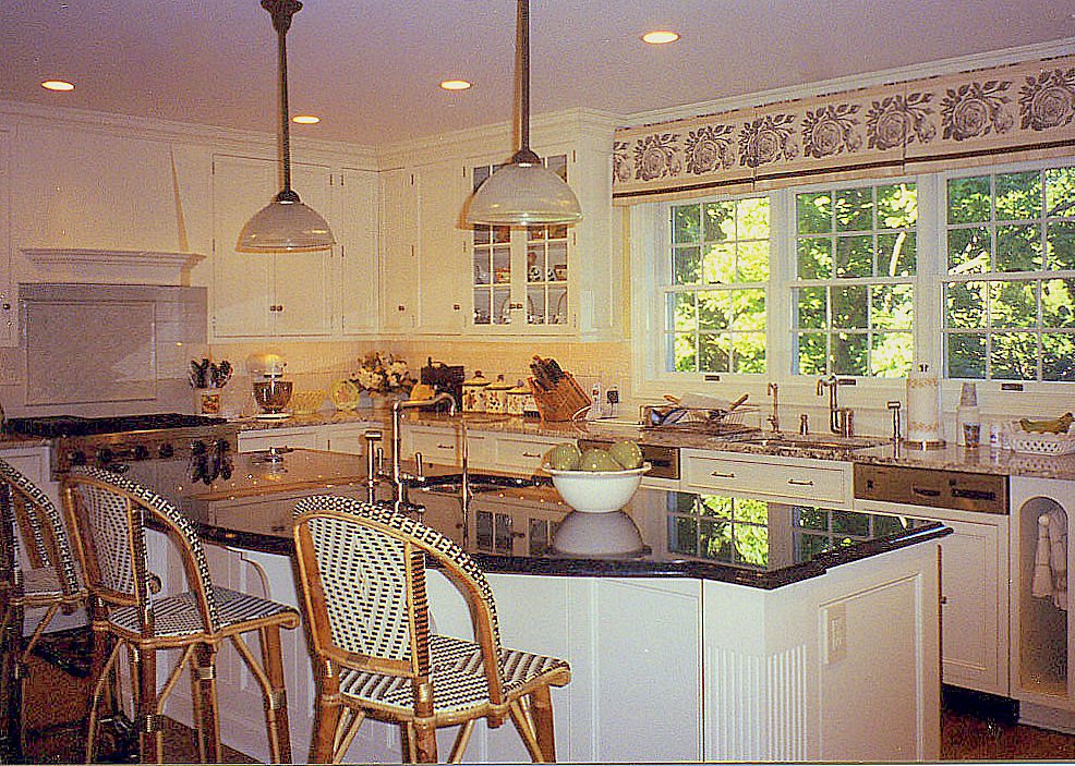 French country kitchen with rattan bistro stools and a black granite island