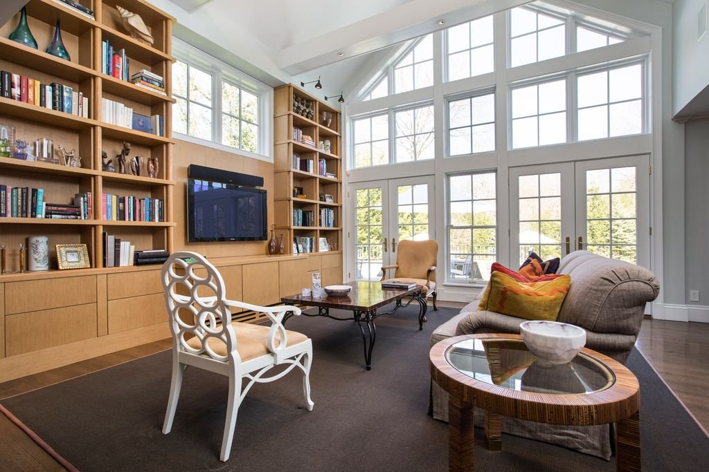 Double-height family room and library with custom maple built-ins and a wall of windows