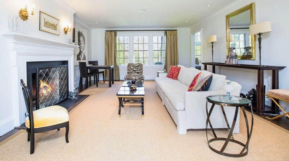 Elegant living room with a white sofa, a gilt mirror, and a fireside seating arrangement